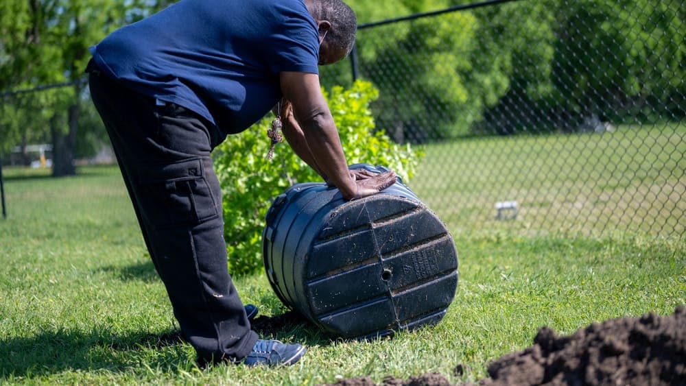 A rotating compost tumbler in a garden